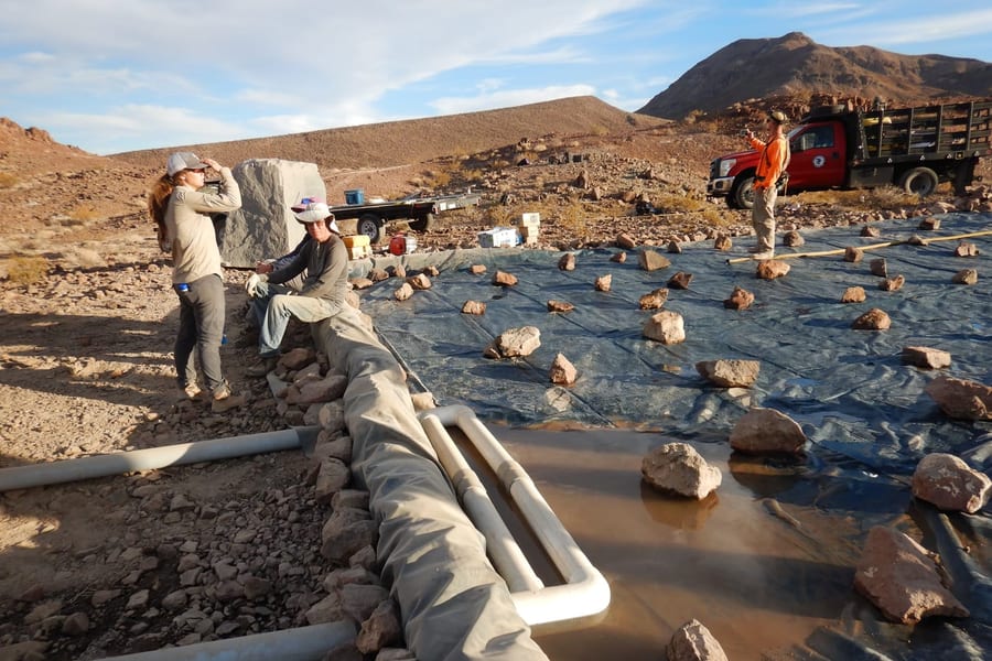 Volunteers weighting down the rain collection mat with rock at the Aurora site