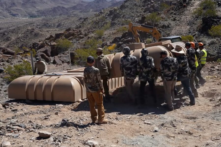 A crew walking a row of tanks down into the hillside trench at Kuiu Gulch