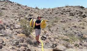 A volunteer carrying a coil of fire hose across the desert